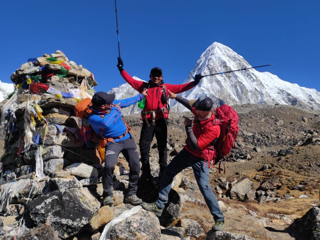 3 men happily enjoying their trek in front of Mt. Pumori.